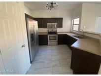 A kitchen featuring stainless steel appliances, tile flooring, and dark wood cabinets at 525 N Miller Rd # 239, Scottsdale, AZ 85257