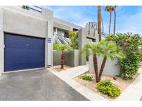 View of the building exterior showing landscaping, the entrance to unit 102, and an electric blue garage door at 902 W Glendale Ave # 102, Phoenix, AZ 85021