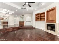 Open-concept living room with hardwood floors, a fireplace, built-in cabinets, and stairs at 902 W Glendale Ave # 102, Phoenix, AZ 85021
