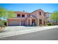Two-story home featuring a three-car garage, stone accents, and a well-manicured front yard at 26703 N 90Th Dr, Peoria, AZ 85383