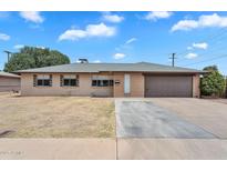 Charming single-story home featuring a two-car garage and a large front yard with mature landscaping at 4102 W Golden Ln, Phoenix, AZ 85051