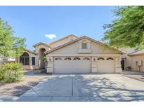 Beige stucco home with a three-car garage and manicured landscaping under a bright blue sky at 4353 W Walton Way, Chandler, AZ 85226