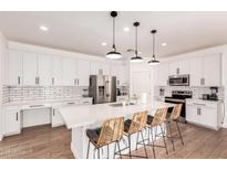 Bright kitchen features white cabinetry, stainless steel appliances, and a center island with seating at 512 E Bamboo Ln, San Tan Valley, AZ 85140