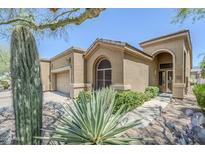 Inviting desert home with lush xeriscaping, mature cactus, and an attached two-car garage at 7094 E Palo Brea Dr, Gold Canyon, AZ 85118