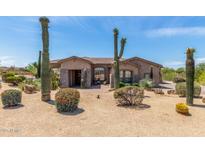 Desert landscaping enhances this tan home featuring a tile roof and stone accents on the columns and entry at 8725 E Menlo Cir, Mesa, AZ 85207