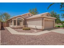 Charming single-story home featuring a tan exterior, well-maintained landscaping, and a two-car garage in a sunny setting at 13241 W Desert Ln, Surprise, AZ 85374