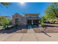 Charming two-story home with a welcoming front porch and desert landscaping under a bright blue sky at 20557 W Lost Creek Dr, Buckeye, AZ 85396