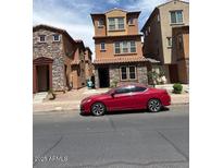 Charming three-story home with low maintenance landscaping and a red sports car parked on the street at 2111 N 77Th Gln, Phoenix, AZ 85035