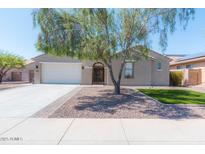 Charming single-story home with a two-car garage, complemented by mature landscaping and a welcoming entrance gate at 30308 W Whitton Ave, Buckeye, AZ 85396
