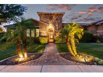 Stunning front exterior of home with stone accents, a brick walkway, lush greenery, and swaying palm trees at twilight at 3460 E Lynx Pl, Chandler, AZ 85249