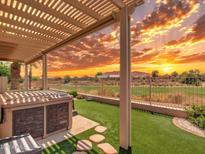 Stunning covered back patio with hot tub overlooks lush green space and a vibrant sunset at 11547 W King Snake Ct, Surprise, AZ 85378