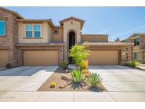 Inviting townhome featuring two-car garage, desert landscaping, and charming architectural details at 2425 W Bronco Butte Trl # 2028, Phoenix, AZ 85085