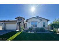 Beautiful single-story home featuring stone accents, a well-manicured lawn, and a three-car garage at 25602 S 229Th Pl, Queen Creek, AZ 85142