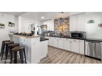 Modern kitchen with white cabinetry, black countertops, stainless steel appliances, and stylish backsplash at 3330 E Cypress St, Phoenix, AZ 85008