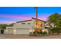 Striking two-story home with a three-car garage and mature landscaping against a colorful dusk sky at 4824 E Hummingbird Ln, Paradise Valley, AZ 85253