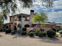 Beautiful exterior of a two-story home with stone accents, a balcony and a landscaped yard at 7751 E Golden Eagle Cir, Gold Canyon, AZ 85118