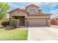 Charming two-story home featuring a well-maintained lawn, stone accents, and a spacious two-car garage at 7812 S 67Th Ln, Laveen, AZ 85339