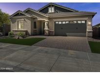 Beautiful single-Gathering home with a well-manicured lawn, brick driveway, and two car garage at 16006 W Electra Ln, Surprise, AZ 85387