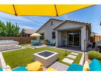 Inviting backyard featuring artificial turf, hot tub, a fire pit and stylish outdoor seating for relaxation and entertainment at 25289 N 143Rd Dr, Surprise, AZ 85387