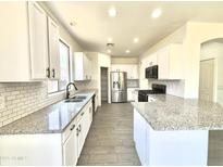 Modern kitchen with stainless steel appliances, granite countertops, and white cabinets offers a clean, stylish design at 7116 W Sophie Ln, Laveen, AZ 85339