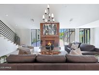 Bright living room featuring a striking brick fireplace, modern chandelier, and stylish furniture at 733 W El Camino Dr, Phoenix, AZ 85021