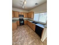 Well-lit kitchen featuring tile flooring, black appliances, wood cabinetry and a black double basin sink at 1015 S Val Vista Dr # 52, Mesa, AZ 85204