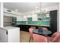 A stylish kitchen with black and white cabinets, modern lighting, and a unique geometric backsplash at 1225 E Medlock Dr # 206, Phoenix, AZ 85014