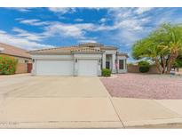 Charming single-story home boasts a three-car garage, tile roof, and neat landscaping at 13368 W Rimrock St, Surprise, AZ 85374