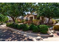 Charming home featuring a cozy front porch framed by lush green trees and manicured bushes at 13602 N 149Th Ave, Surprise, AZ 85379