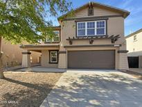 Two-story home featuring a two-car garage and a well-maintained front yard, showcasing its inviting curb appeal at 18148 W Lundberg St, Surprise, AZ 85388
