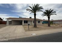 Single story home featuring a covered parking area, desert landscaping, and two palm trees at 3749 W Gelding Dr, Phoenix, AZ 85053
