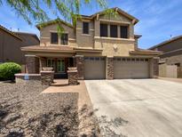 Inviting two-story home showcasing a three-car garage and a charming stone-accented entryway at 5140 W Bent Tree Dr, Phoenix, AZ 85083