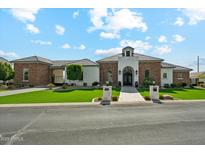Beautiful single-story home with a stone and white facade, lush green lawn, and well-manicured landscaping at 7482 S Mccormick Way, Queen Creek, AZ 85142