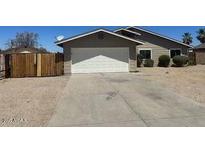 Charming single-story home featuring a two-car garage, desert landscaping, and a wooden privacy fence at 11044 N 75Th Dr, Peoria, AZ 85345