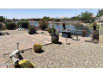 Beautiful backyard with a lake view, desert landscaping, and a firepit with seating, perfect for outdoor entertaining at 16858 S 180Th Ave, Goodyear, AZ 85338