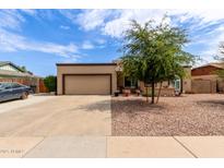 Tan single-story home featuring a gravel yard, mature tree, and attached two-car garage at 317 E Harwell Rd, Gilbert, AZ 85234