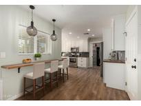 Bright kitchen featuring white cabinets, stainless steel appliances, breakfast bar and stylish pendant lighting at 4939 E Paradise Dr, Scottsdale, AZ 85254