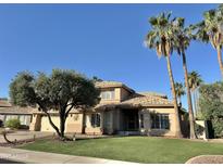 Charming tan two-story home with tile roof, palm trees, manicured lawn, and desert landscaping at 2549 E Desert Trumpet Rd, Phoenix, AZ 85048