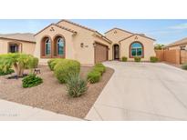 Charming single-story home featuring a tile roof, arched windows, a two-car garage, and professionally landscaped front yard at 25947 W Oraibi Dr, Buckeye, AZ 85396