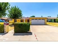 Charming yellow single-story home boasts a well-maintained front yard and attached two car garage at 9714 N 55Th Dr, Glendale, AZ 85302