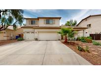 Tan two-story home featuring a spacious three-car garage and desert landscaping at 10441 W Windsor Ave, Avondale, AZ 85392