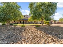 Spacious home featuring desert landscaping, a stone-lined drainage path, and mature trees at 1409 E Dove Pl, Casa Grande, AZ 85122