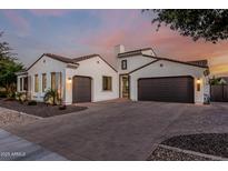 Stunning single-story home featuring a paver driveway and a three-car garage, set against a vibrant sunset sky at 1725 E Everglade Ln, Gilbert, AZ 85298