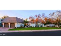 Charming home featuring a terra cotta roof, white stucco walls, and mature landscaping at 18 W Kaler Dr, Phoenix, AZ 85021
