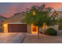 Charming two-story home with a two car garage, desert landscaping, and warm exterior lighting at sunset at 2324 W Melody Dr, Phoenix, AZ 85041