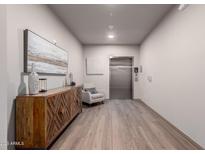 Hallway with art and a wood cabinet leads to an elevator with wood floors at 2511 W Queen Creek Rd # 174, Chandler, AZ 85248