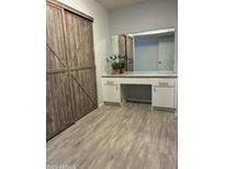 Bedroom with wooden sliding closet doors and a built-in vanity with a mirror at 5303 W Port Au Prince Ln, Glendale, AZ 85306