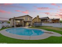 Backyard features a sparkling blue pool, diving board, and an artificial turf lawn that extends to the covered patio at 8912 W Sheridan St, Phoenix, AZ 85037