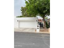 Contemporary home with a white stucco exterior, two car garage, and mature shade tree at 225 W Winged Foot Rd, Phoenix, AZ 85023