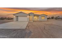 Stunning single-story home boasting a modern design and a large garage under a vibrant sunset sky at 28834 N 175Th Ave, Surprise, AZ 85387